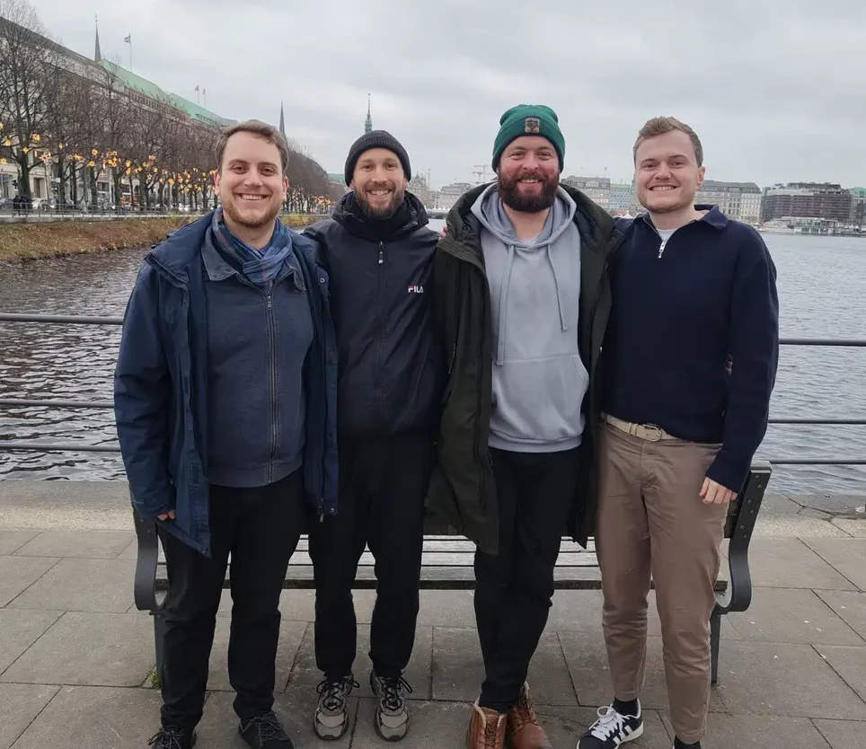 Vier Gründer des Startups A/D-Evolution, nebeneinander stehend am Jungfernstieg, im Hintergrund die Binnenalster