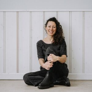 Bild von Sandra-Luisa Moschner, Beraterin, Coach und Facilitatorin für verkörperte Veränderung, auf dem Boden sitzend,